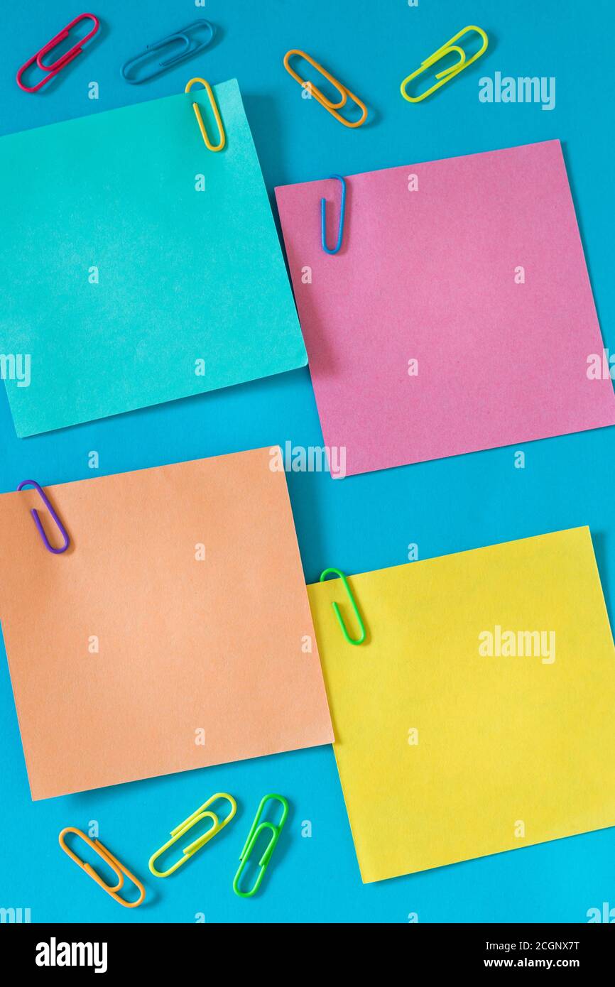 Kleine farbige Haftnotizen mit Büroklammern und Platz für Text, blauer Hintergrund Stockfoto
