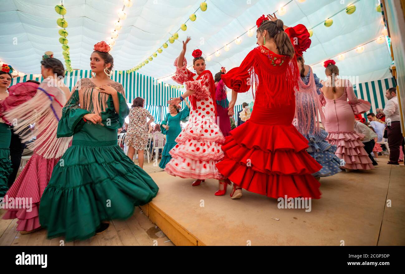Junge Frau, die Sevillano tanzt, Spanierin mit Flamenco-Kleidern im bunten Festzelt, Casetas, Feria de Abril, Sevilla, Andalusien, Spanien Stockfoto