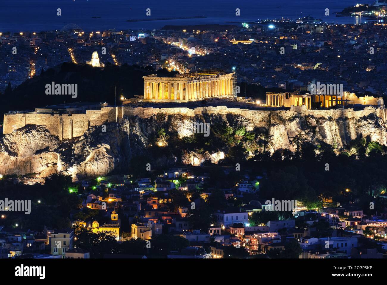 Blick auf Akropolis Parthenon und Erechtheion, Philoppapos Denkmal bei Nacht. Lichter der Stadt Athen. Berühmte ikonische Ansicht des UNESCO-Weltkulturerbes. Stockfoto