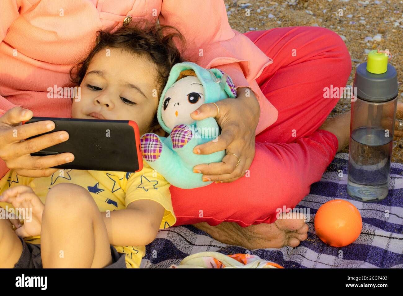 Eine indische Mutter leckt ihren Sohn im Dock und Schaut englische Reime in intelligenten Handys und genießt die offene Und reine Luft einer kleinen asiatischen Familie.concep Stockfoto