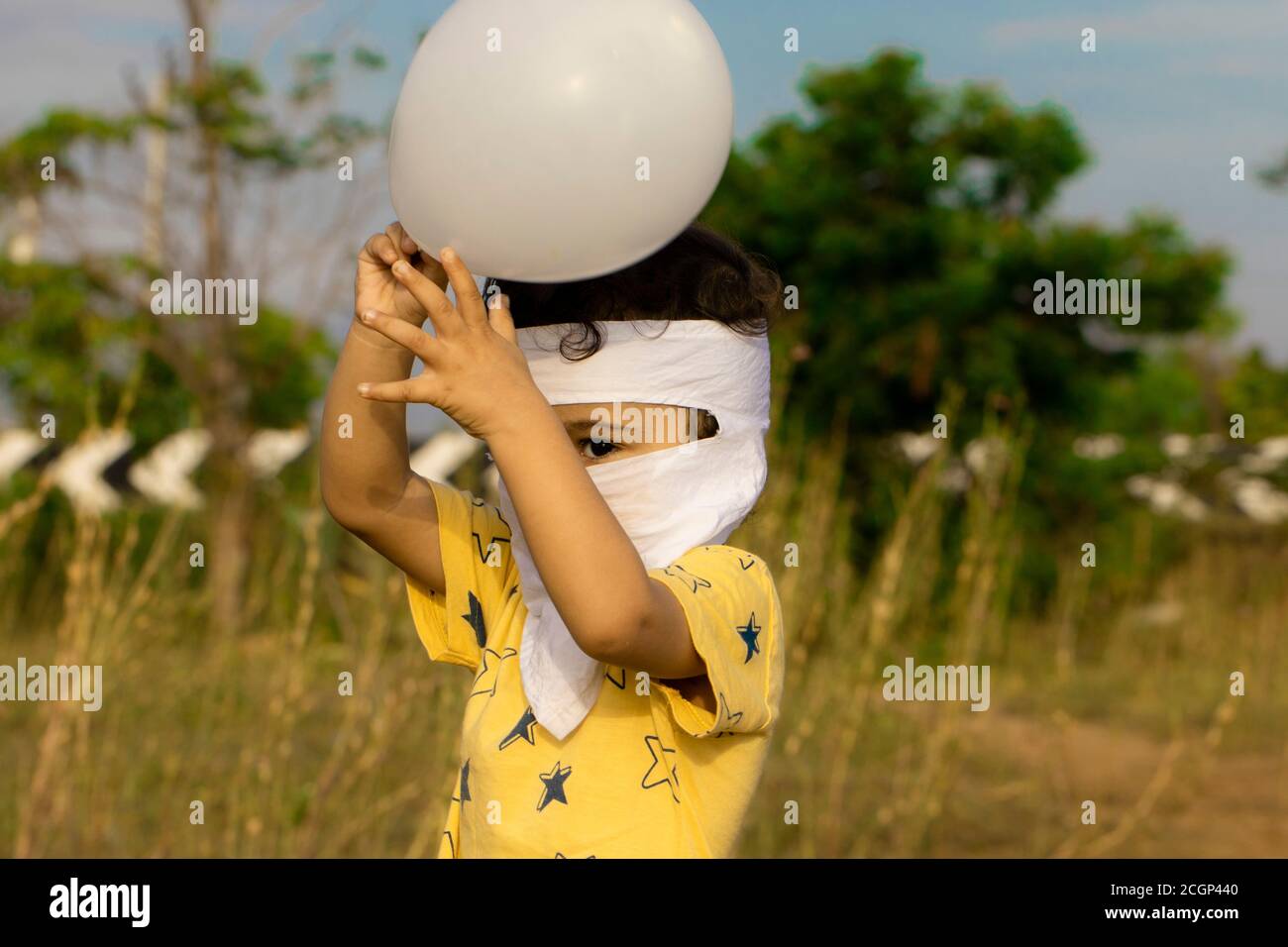 Ein asiatischer Junge genießt das Entriegeln covid-19 und hält weißen Ballon in zwei Händen auf dem Parkplatz in der Nähe ecr Straße von chennai, Kind volles Gesicht mit Maske bedeckt Stockfoto