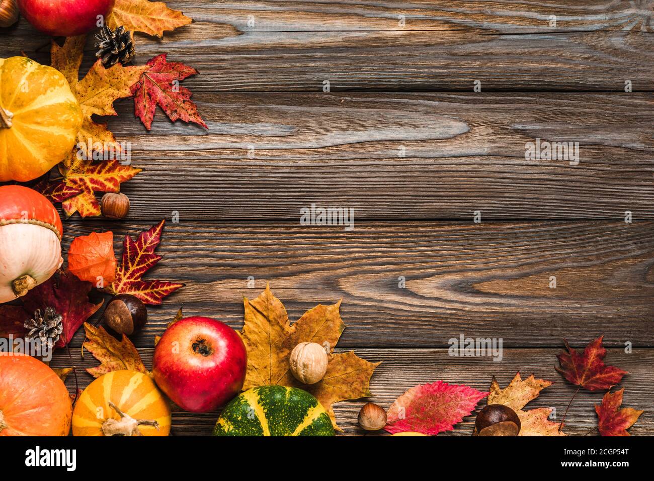 Thanksgiving, Halloween oder Herbst Hintergrund. Herbstzusammensetzung mit Kürbissen, Äpfeln, Blättern, trockenen Blumen und Nüssen auf rustikalem Holztisch. Flach liegend, t Stockfoto