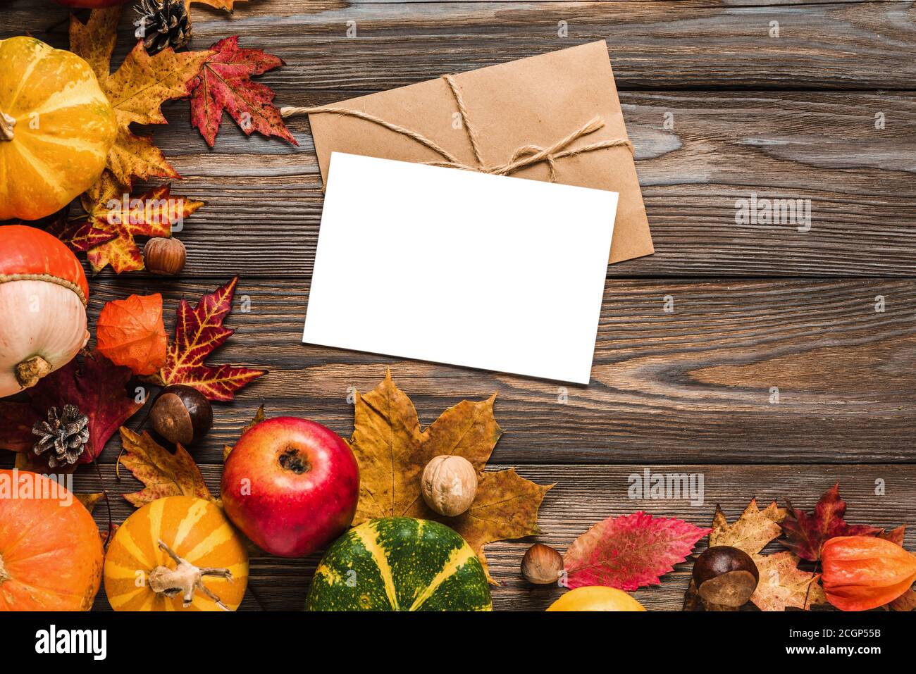 Thanksgiving, Halloween oder Herbst Grußkarte mit Kürbissen, Äpfeln, Blättern, trockenen Blumen und Nüssen auf rustikalem Holztisch. Flach liegend, Mock up. Top vie Stockfoto