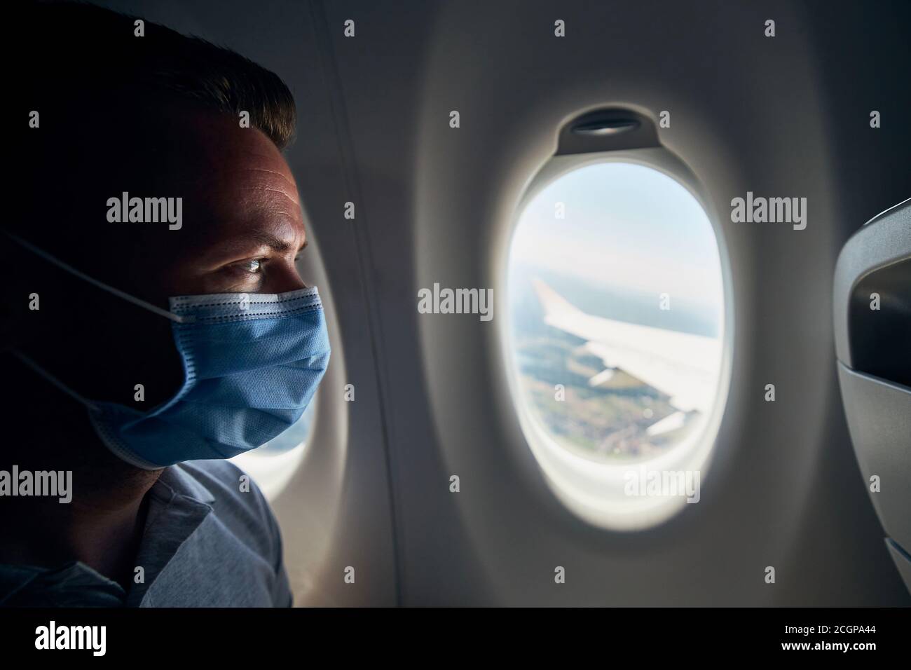 Mann trägt Gesichtsmaske im Flugzeug während des Fluges. Themen neue normale, Coronavirus und persönlichen Schutz. Stockfoto