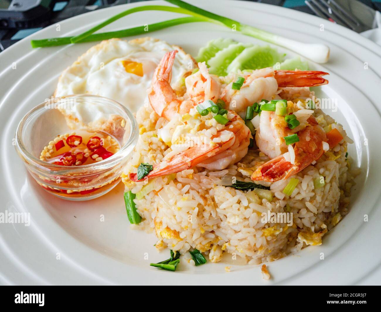 Thai Food: Gebratener Reis mit großen Garnelen, ein Spiegelei und eine kleine Schüssel nam Prik, Fischsauce mit Chili, auf einem Teller. Stockfoto