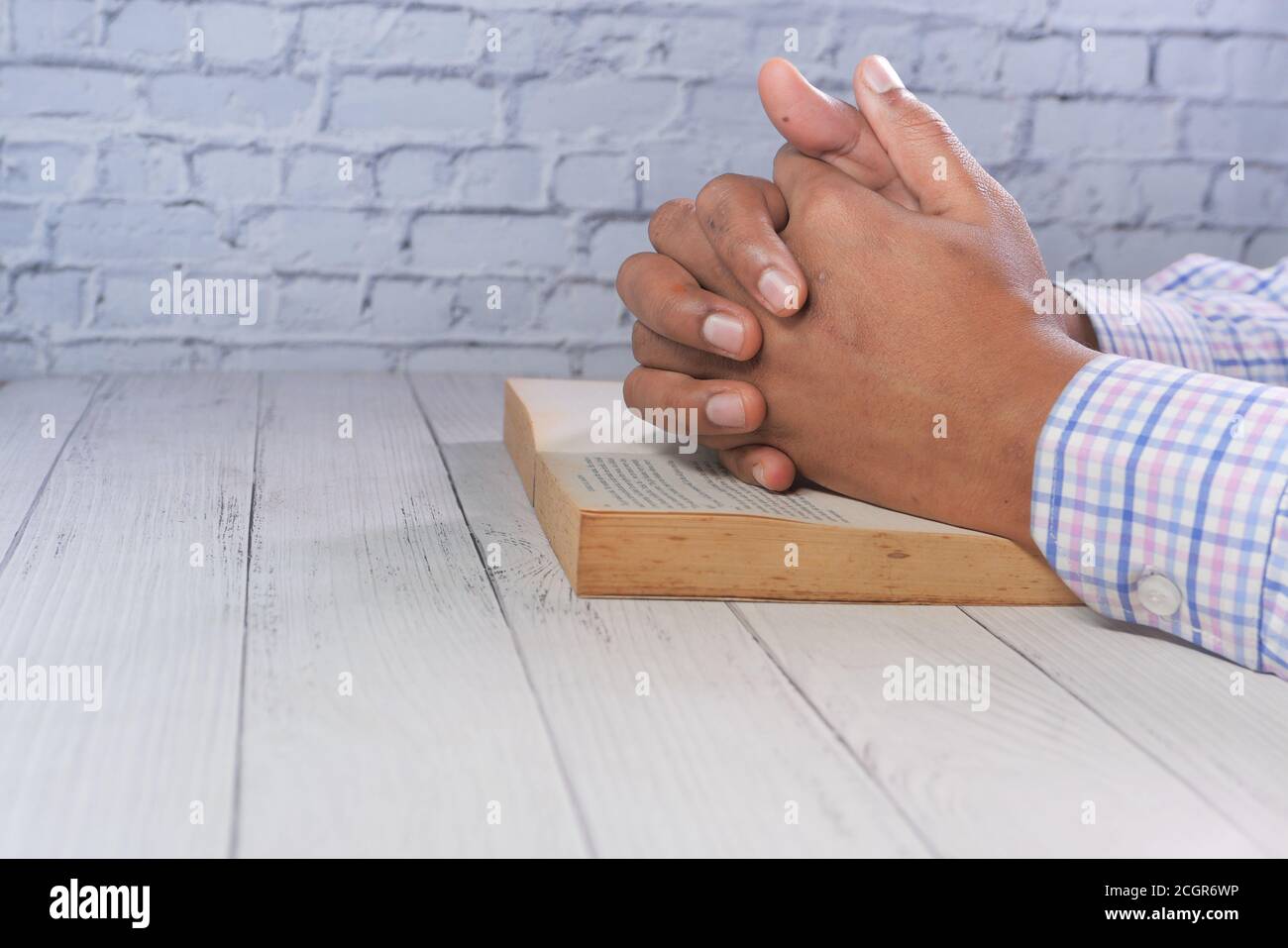 Hände eines Mannes, der über ein Buch betet, Stockfoto