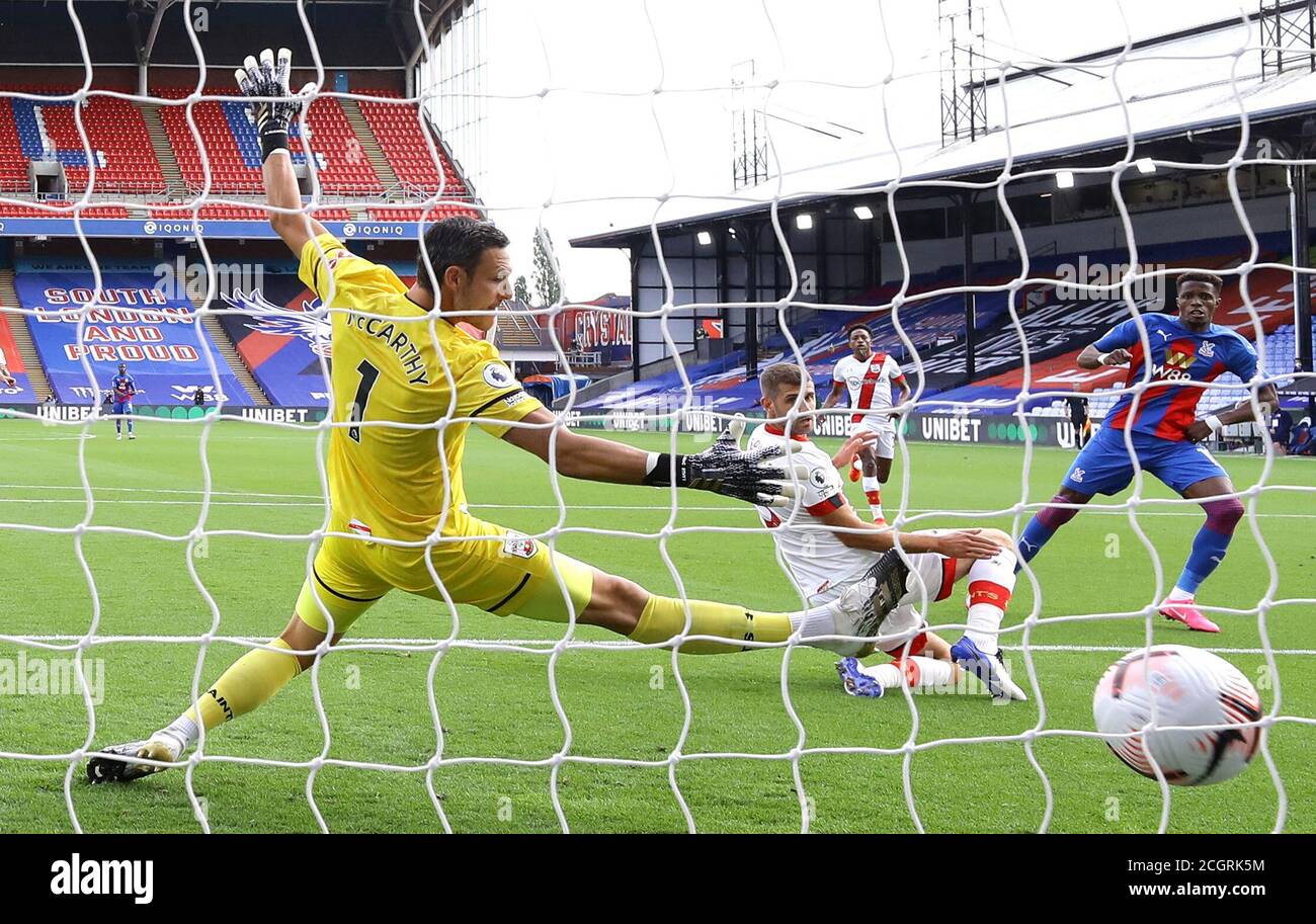 Wilfried Zaha (rechts) von Crystal Palace schlägt Southampton's Alex McCarthy (links), um beim Premier League-Spiel im Selhurst Park, London, das erste Tor seines Teams zu erzielen. Stockfoto