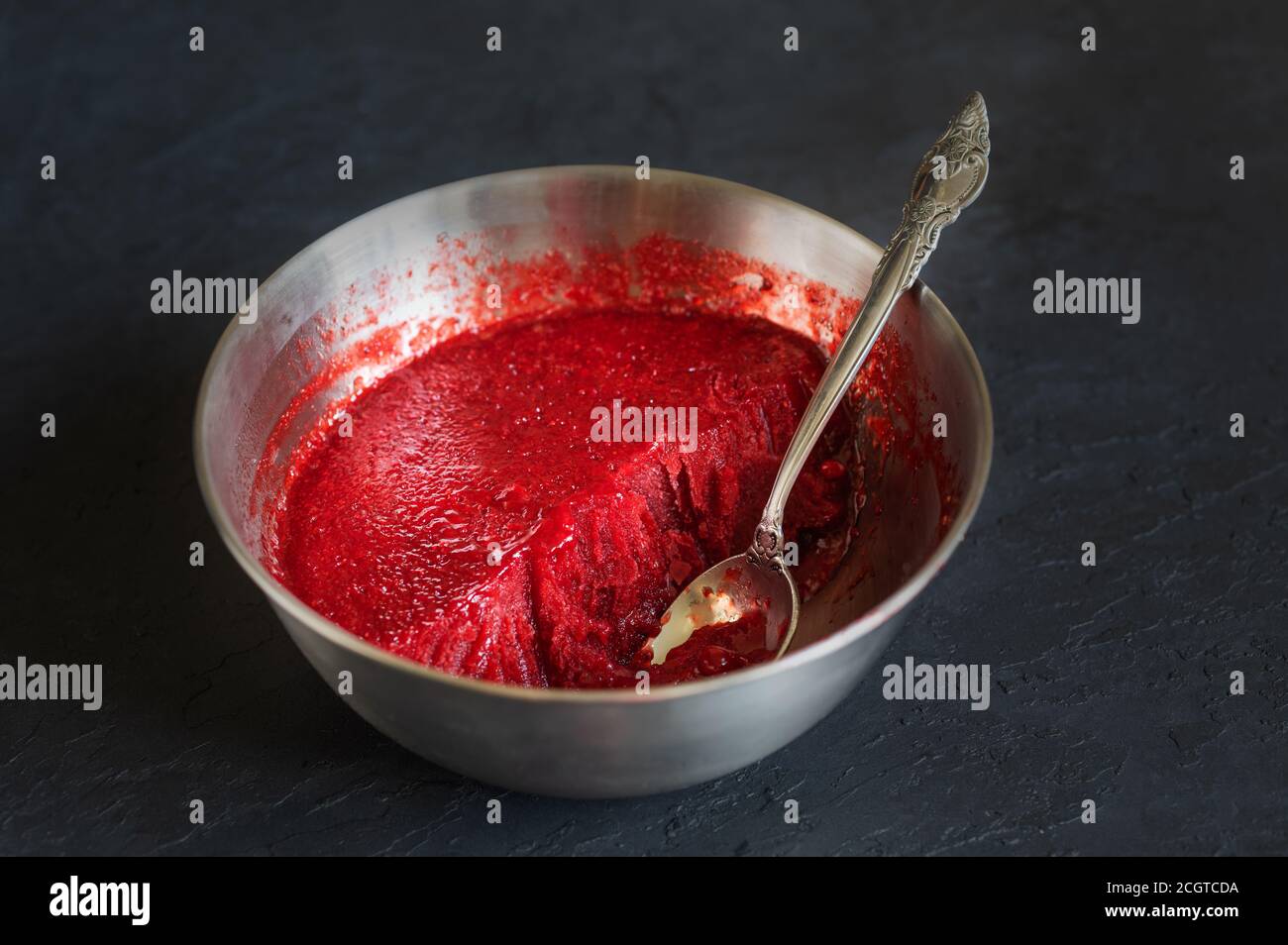 Hausgemachtes Erdbeereis in der Stahlschüssel auf dunklem Hintergrund. Bio-Eis mit Zucker. Stockfoto