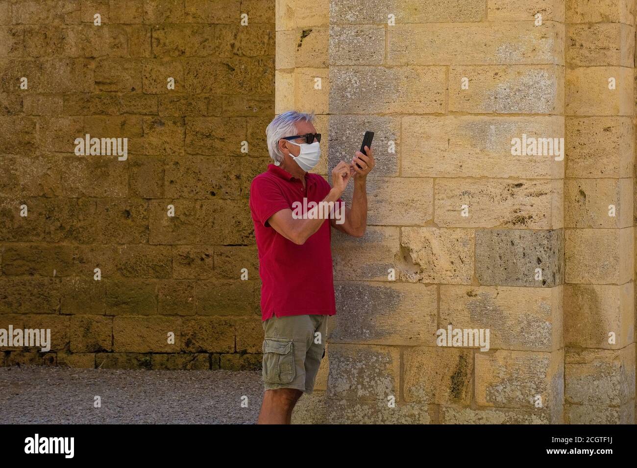 Monticiano, Italien - 7. September 2020. Ein Tourist, der eine Maske trägt, fotografiert mit seinem Telefon in der historischen, dachlosen gotischen Abtei San Galgano aus dem 13. Jahrhundert Stockfoto