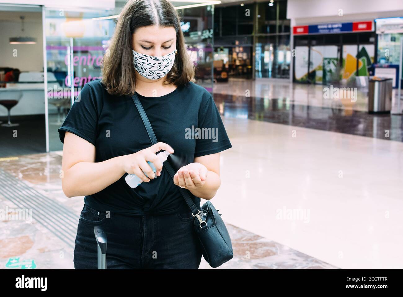 Frau mit Gesichtsmaske desinfiziert ihre Hände mit Hydro-Alkoholiker Gel am Bahnhof Stockfoto