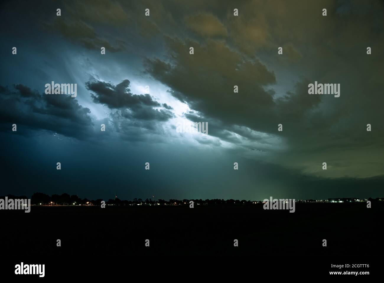Sturmwolken werden von Blitzen beleuchtet. Es sind keine Blitzkanäle sichtbar, da der Weg des Blitzes durch Wolken verdeckt wird. Stockfoto