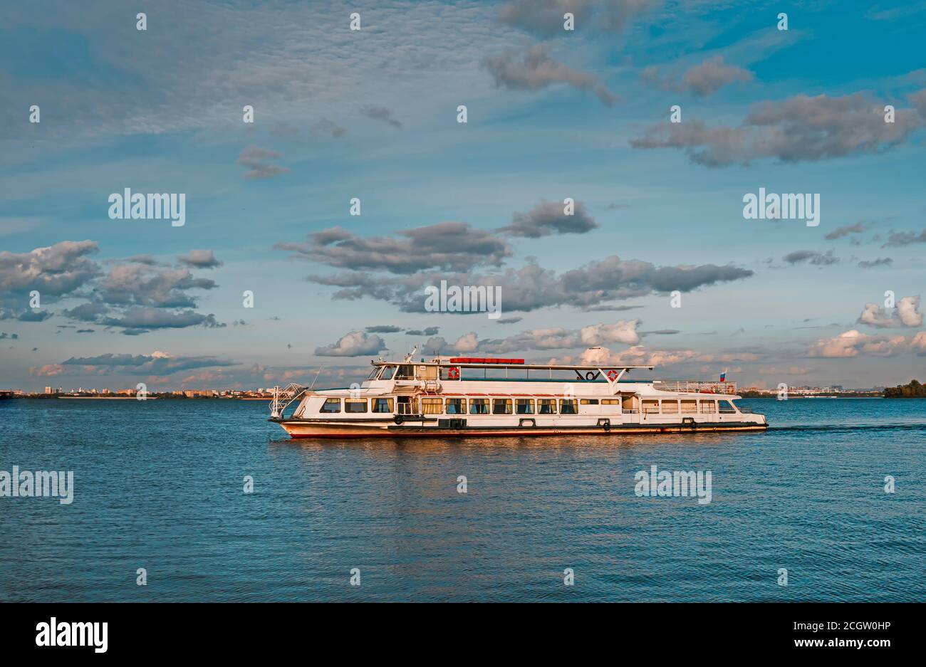 Ein weißes Motorschiff auf dem Fluss unter schönen Wolken. Das Schiff fährt auf dem Fluss Stockfoto