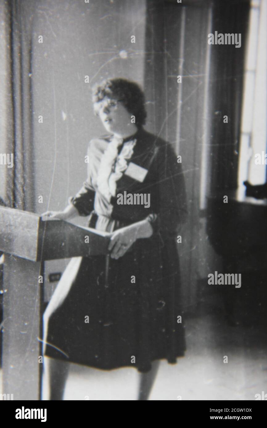 Feine 70er Jahre Vintage Schwarz-Weiß-Fotografie einer Sprecherin, die auf dem Podium steht und eine Adresse liefert. Stockfoto