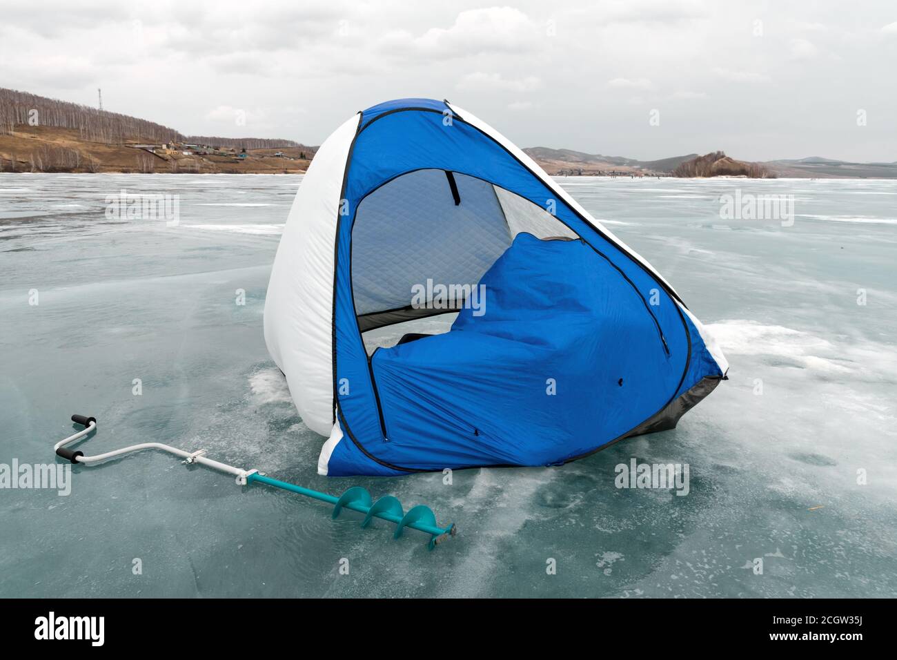 Ein Fischerzelt steht im Wind auf dem schmelzenden Eis des Big Lake gegen das Ufer. Region Krasnojarsk. Russland. Stockfoto