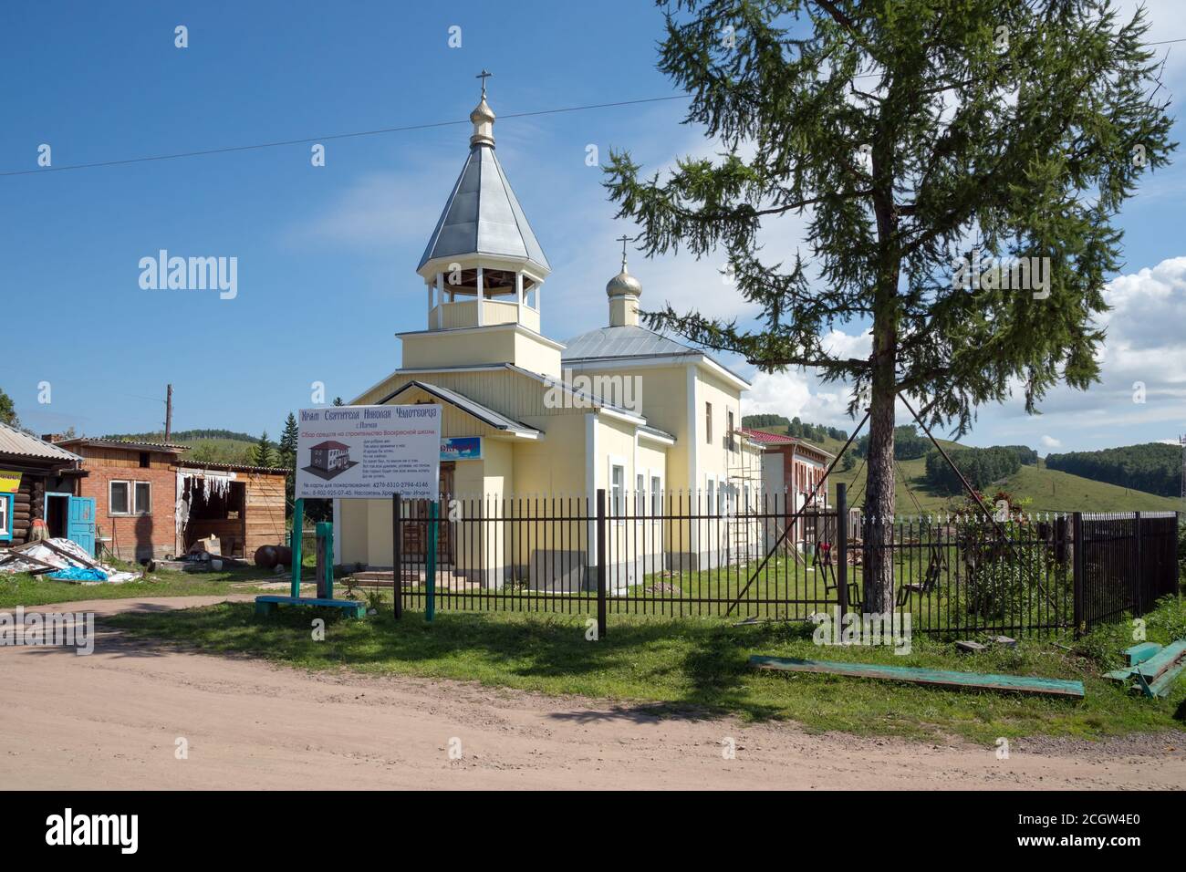 Kirche des heiligen Nikolaus des Wundertäters (1904) mit einem Plakat über die Spendenbeschaffung für den Bau einer Sonntagsschule an einem sonnigen Sommertag. Stockfoto