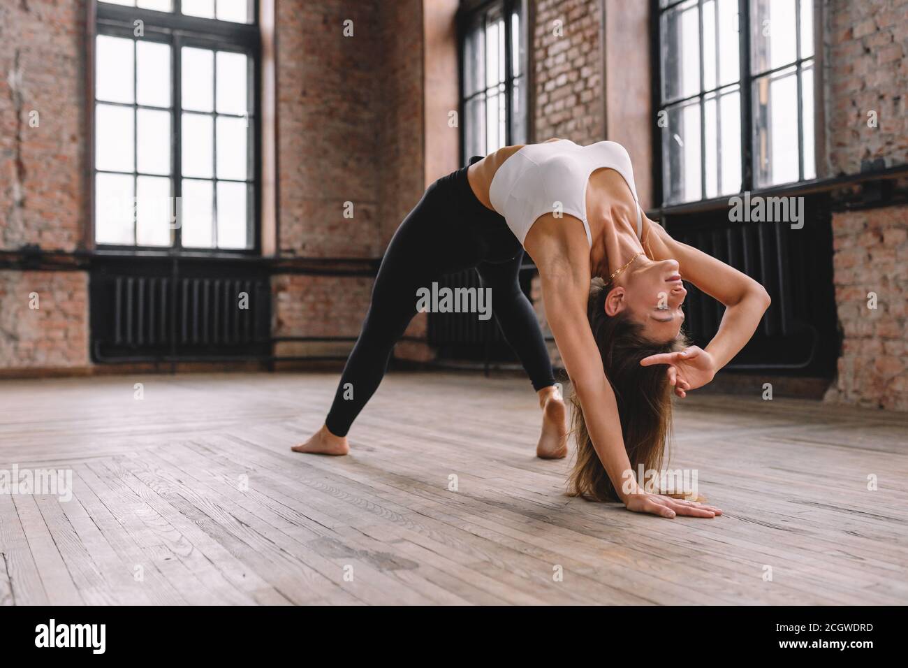 Junge Frau machen Komplex von Stretching Yoga Asanas im Loft-Stil Klasse. Camatkarasana, Wild Thing, Flip-the-Dog Pose. Stockfoto