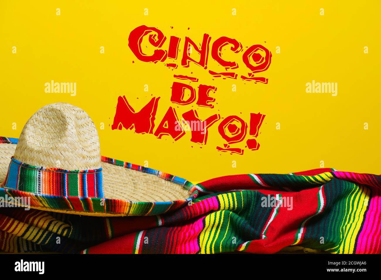 Mexikanische Serape Decke und Sombrero auf gelbem Hintergrund mit Cinco de Mayo. Stockfoto