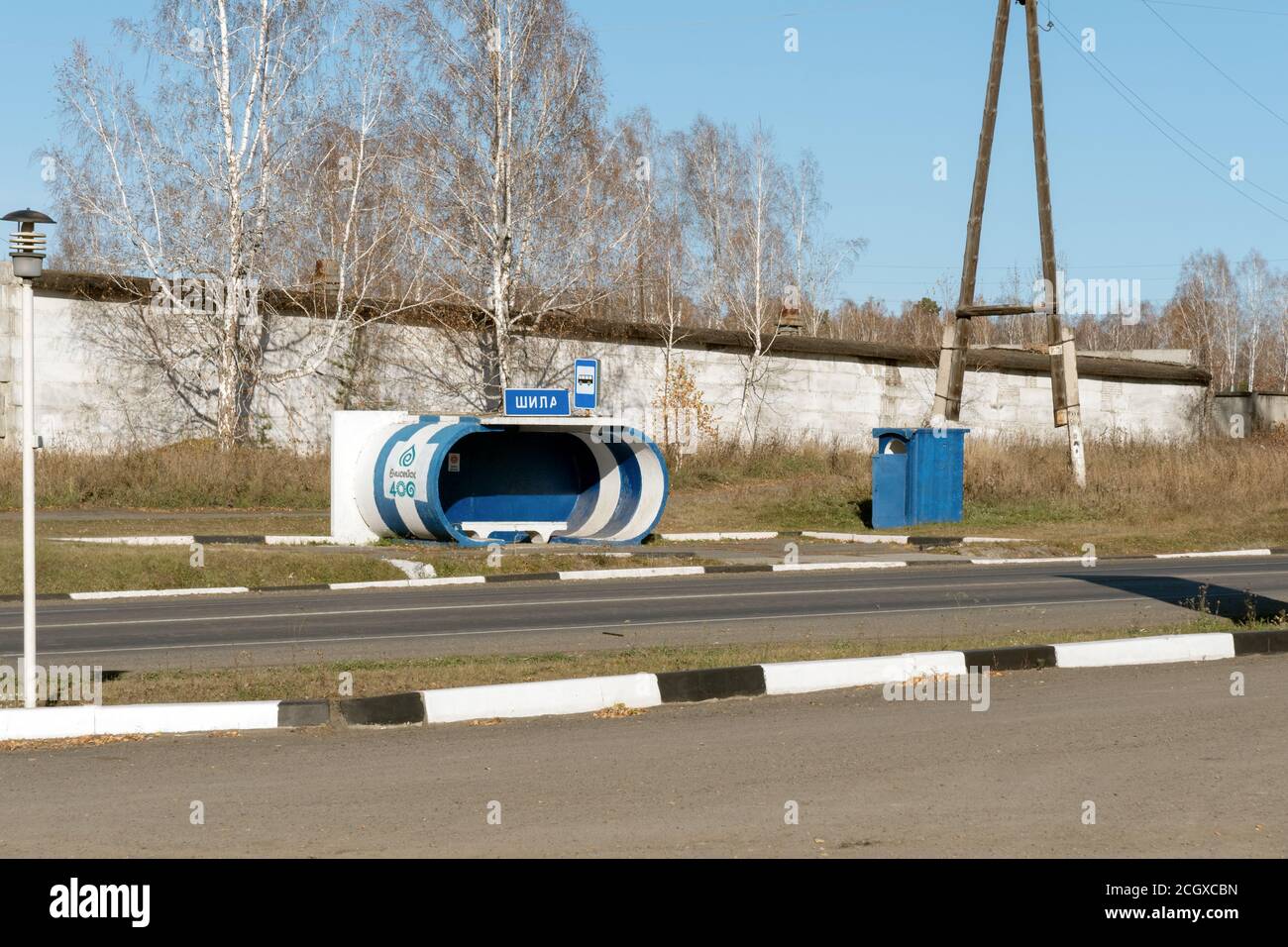 Eine Bushaltestelle für den Intercity-Transport mit einer ländlichen Toilette auf der Autobahn in der Nähe des Dorfes Shila an einem sonnigen Tag im Herbst. Stockfoto