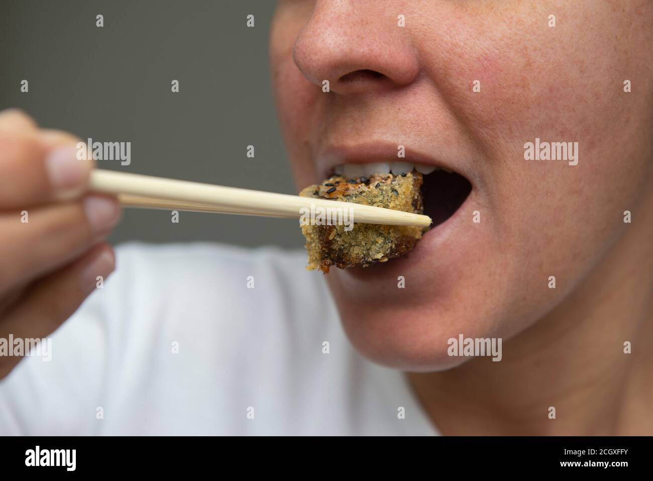 Nahaufnahme des Frauenmundes beim Essen von köstlichem Lachs-Sushi (Hot Roll). Japanische Küche. Selektiver Fokus. Japanische Küche. Stockfoto