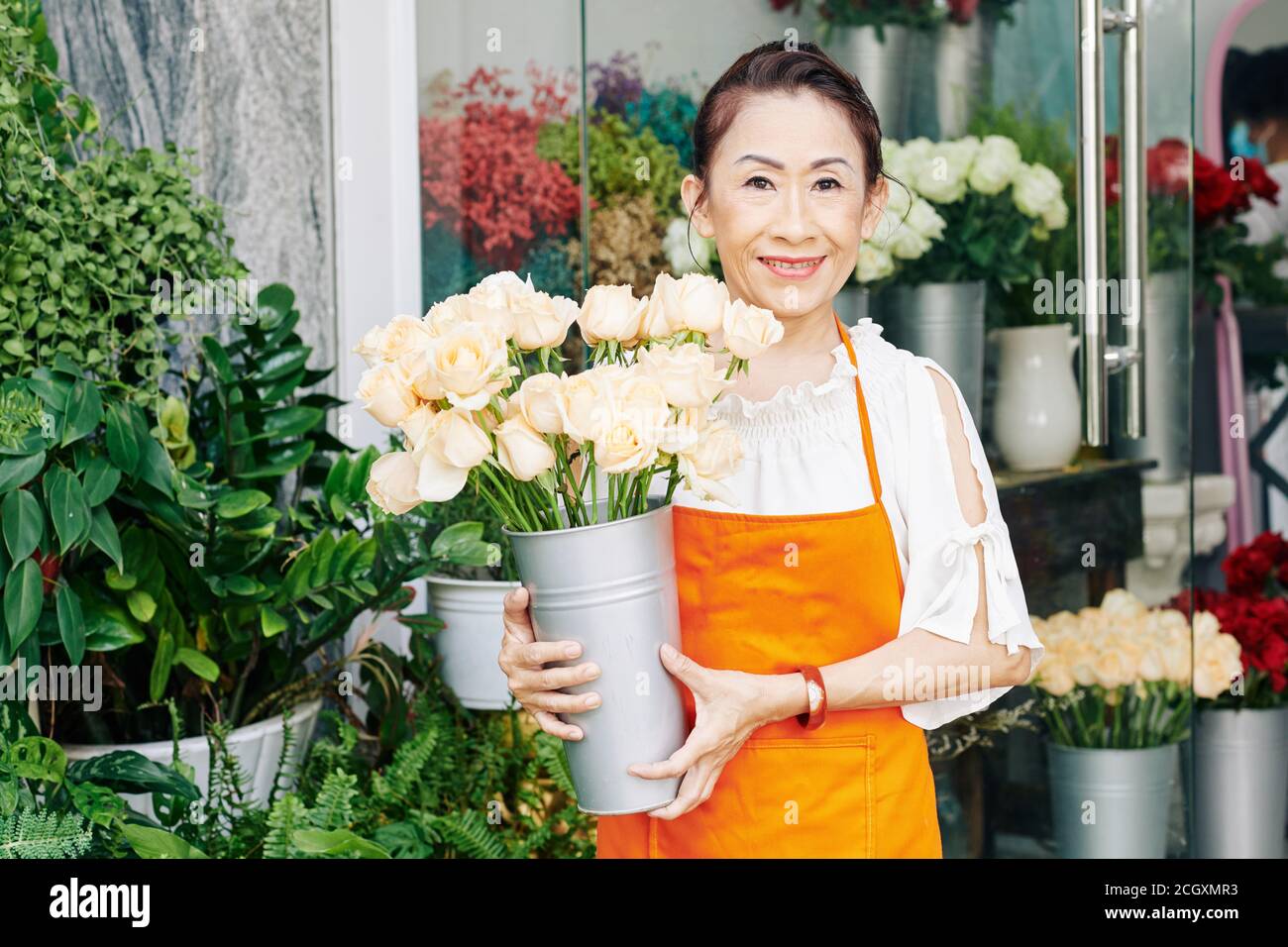 Senior Floristen mit Eimer frische Rosen Stockfoto
