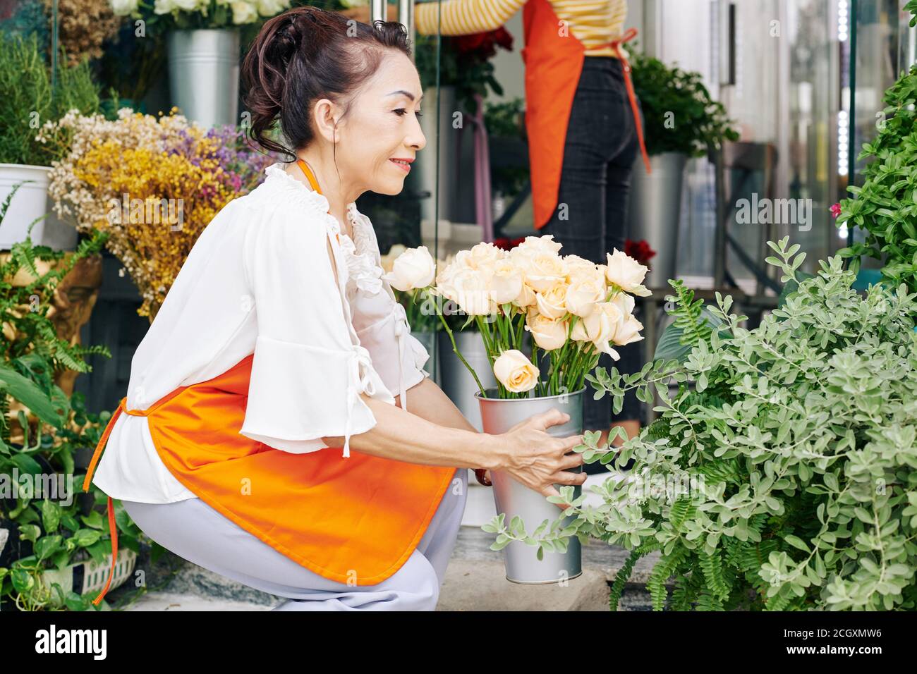 Frau, die Blumen im Laden arrangiert Stockfoto