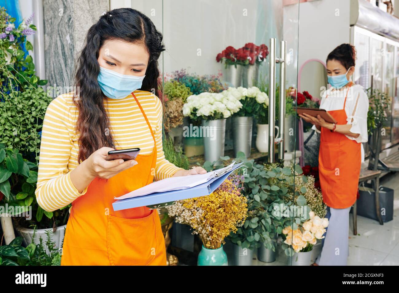 Florist prüft Benachrichtigungen auf dem Smartphone Stockfoto