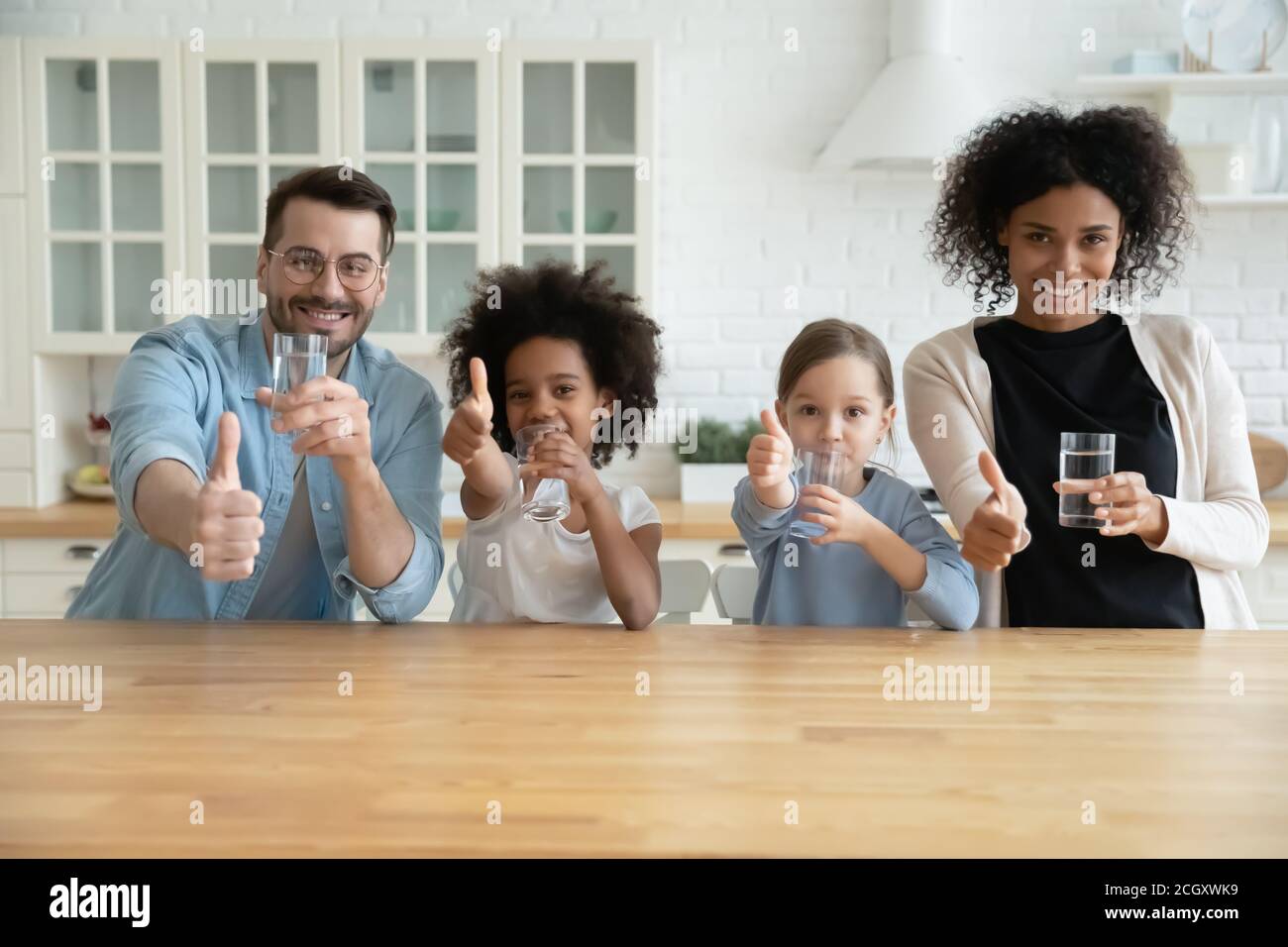 Glückliche gesunde gemischte Rasse Familie empfehlen Trinkwasser. Stockfoto