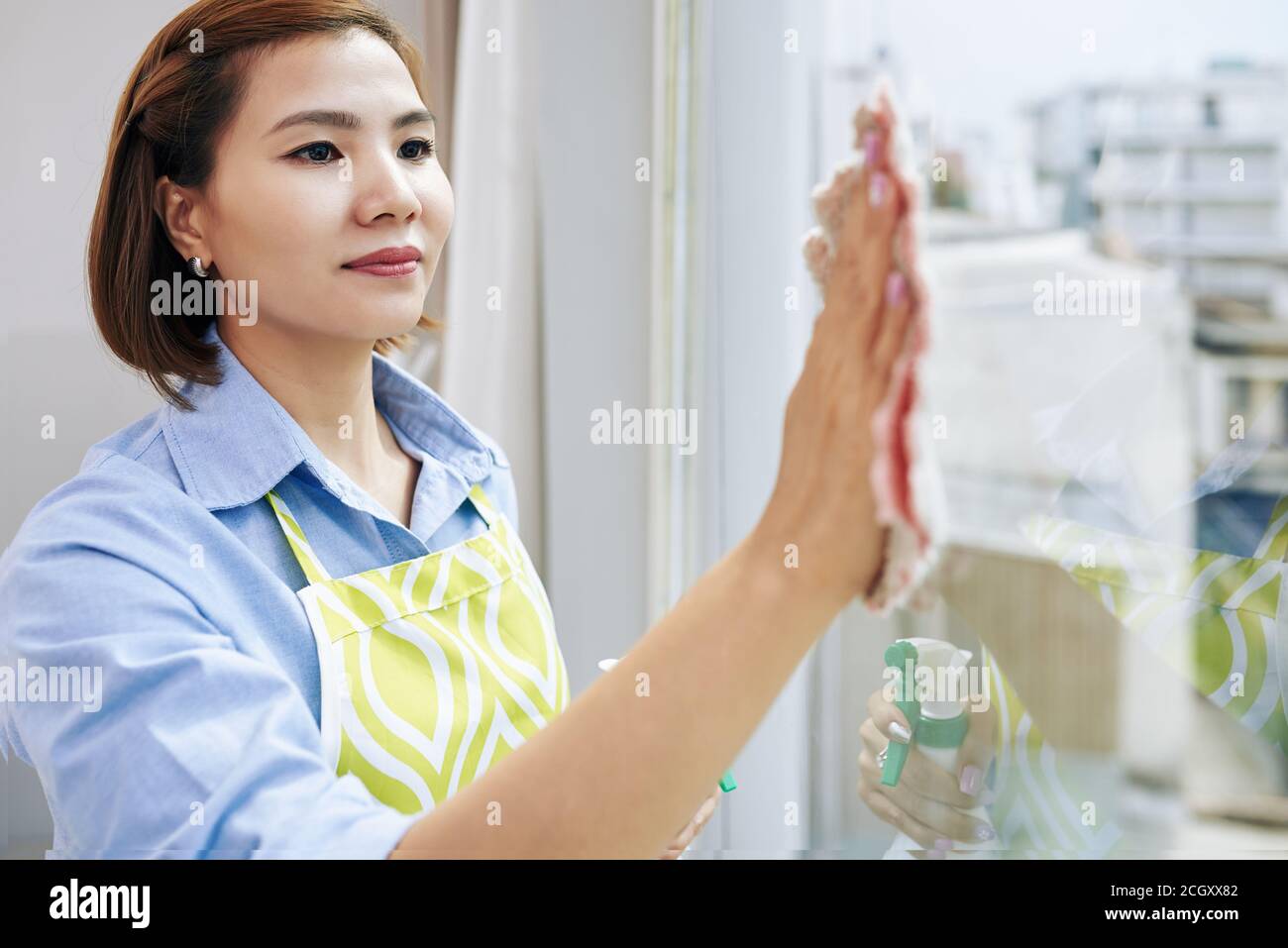 Asiatische Frau putzt Fenster Stockfoto