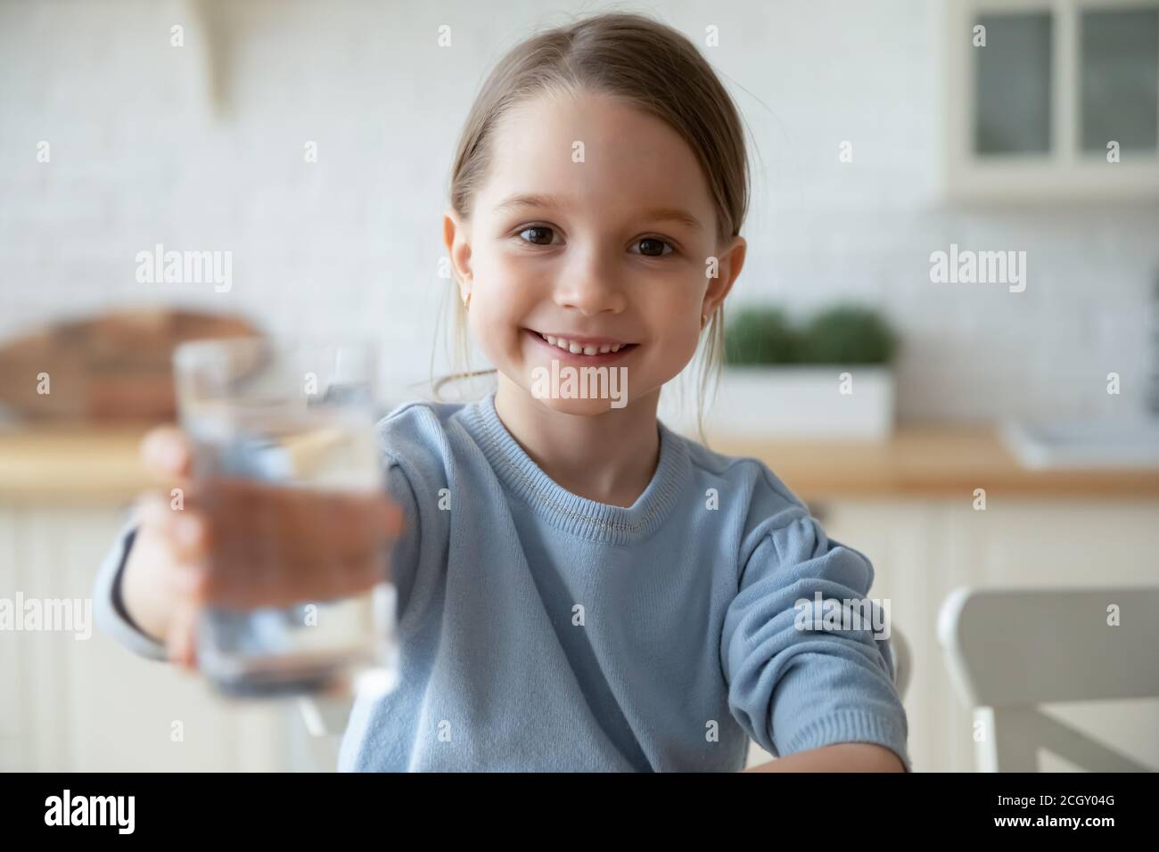 Kleine europäische Mädchen mit Glas mit frischem Aqua. Stockfoto