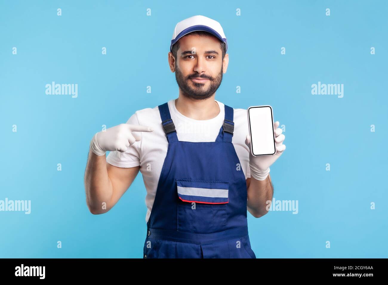 Workman in Overalls und Handschuhe zeigen Handy mit Mock-up leere Display, Werbefläche für Online-Lieferung bestellen App, Hausreparatur maintena Stockfoto