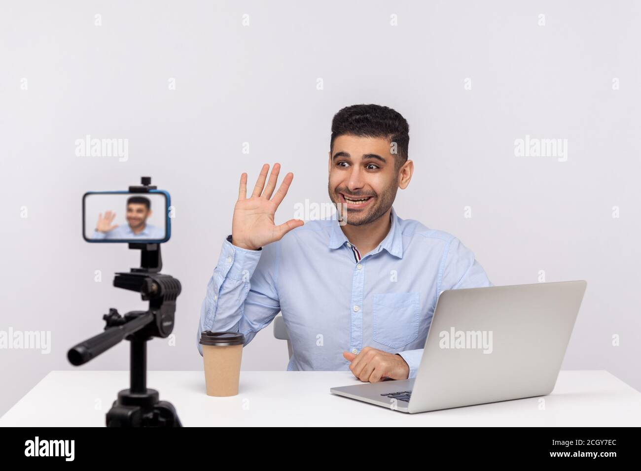 Online-Webinar, Fernschulung. Aufgeregt erfolgreichen Geschäftsmann sitzen am Arbeitsplatz, winkt hallo auf Handy während der Aufnahme Kurs, tun Blog Stockfoto