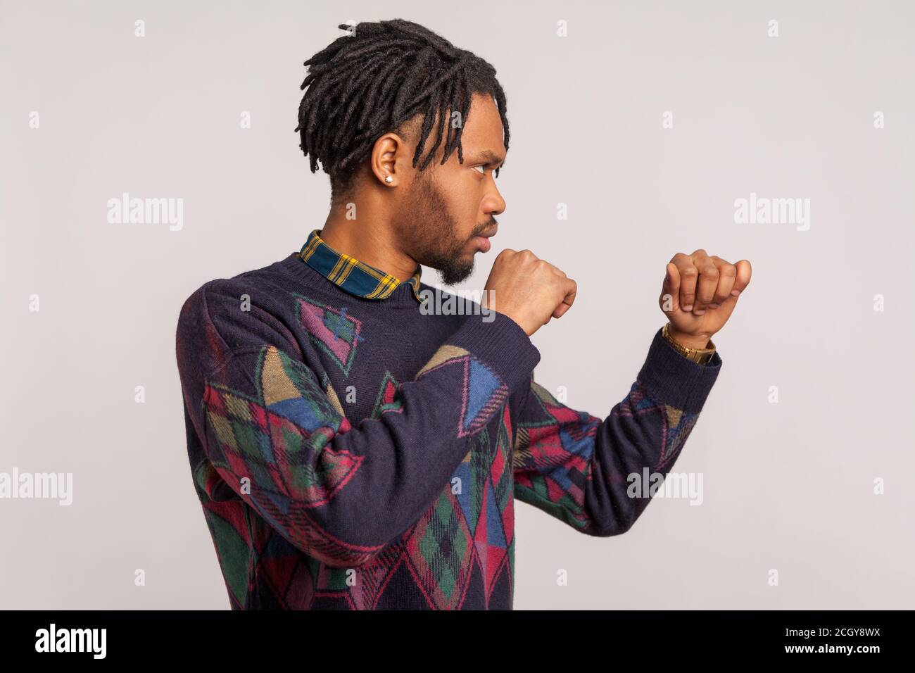 Profilportrait ernsthafter aggressiver afrikanischer Mann mit Dreadlocks, die geballte Fäuste zum Boxen bereithalten und seine Rechte und Freiheit verteidigen. Innenst Stockfoto