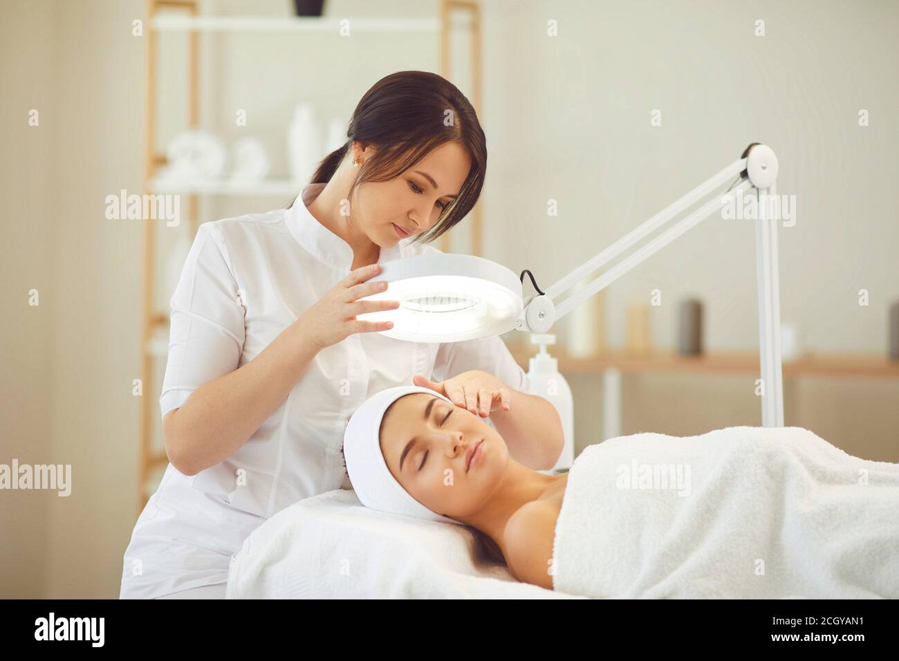 Entspannte junge Frau genießen professionelle Hautpflege-Verfahren in moderner Schönheit Salon Stockfoto