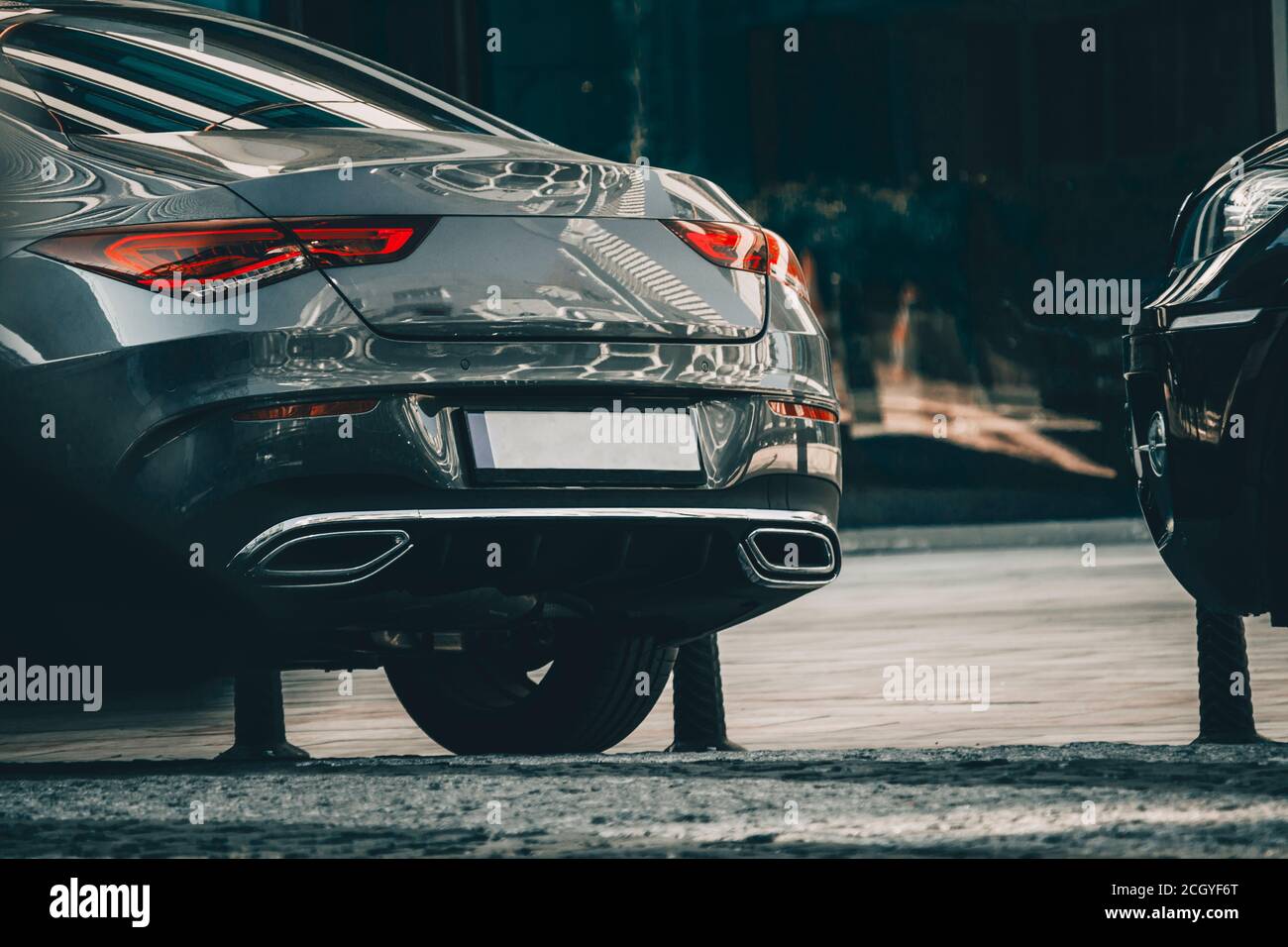 Moderner neuer, glänzender Sportwagen an einer Parkreihe. Wolkenkratzer reflektieren das Auto. Stockfoto