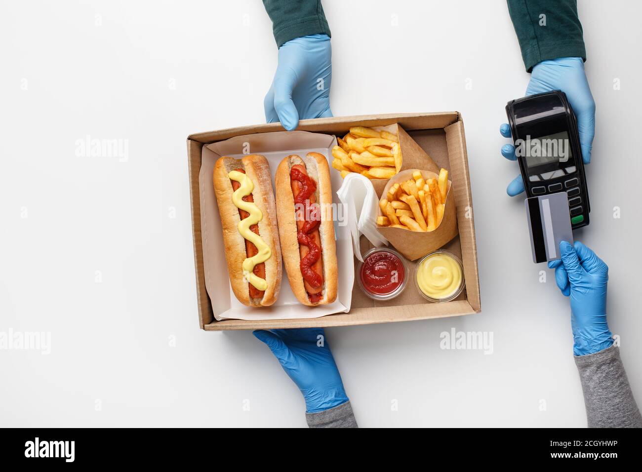 Schnellimbiss und kontaktlose Lieferung während der Quarantäne. Pommes Frites in Öko-Verpackungen, Hot Dogs mit Ketchup und Senf in Behältern Stockfoto