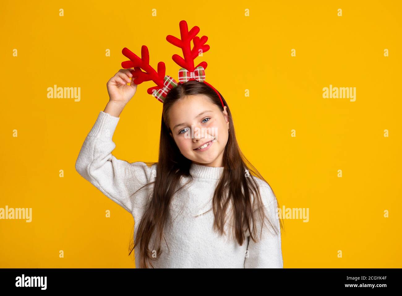 Frohe Kindheit und Weihnachten. Fröhliches Mädchen mit Hörnern in Pullover Stockfoto