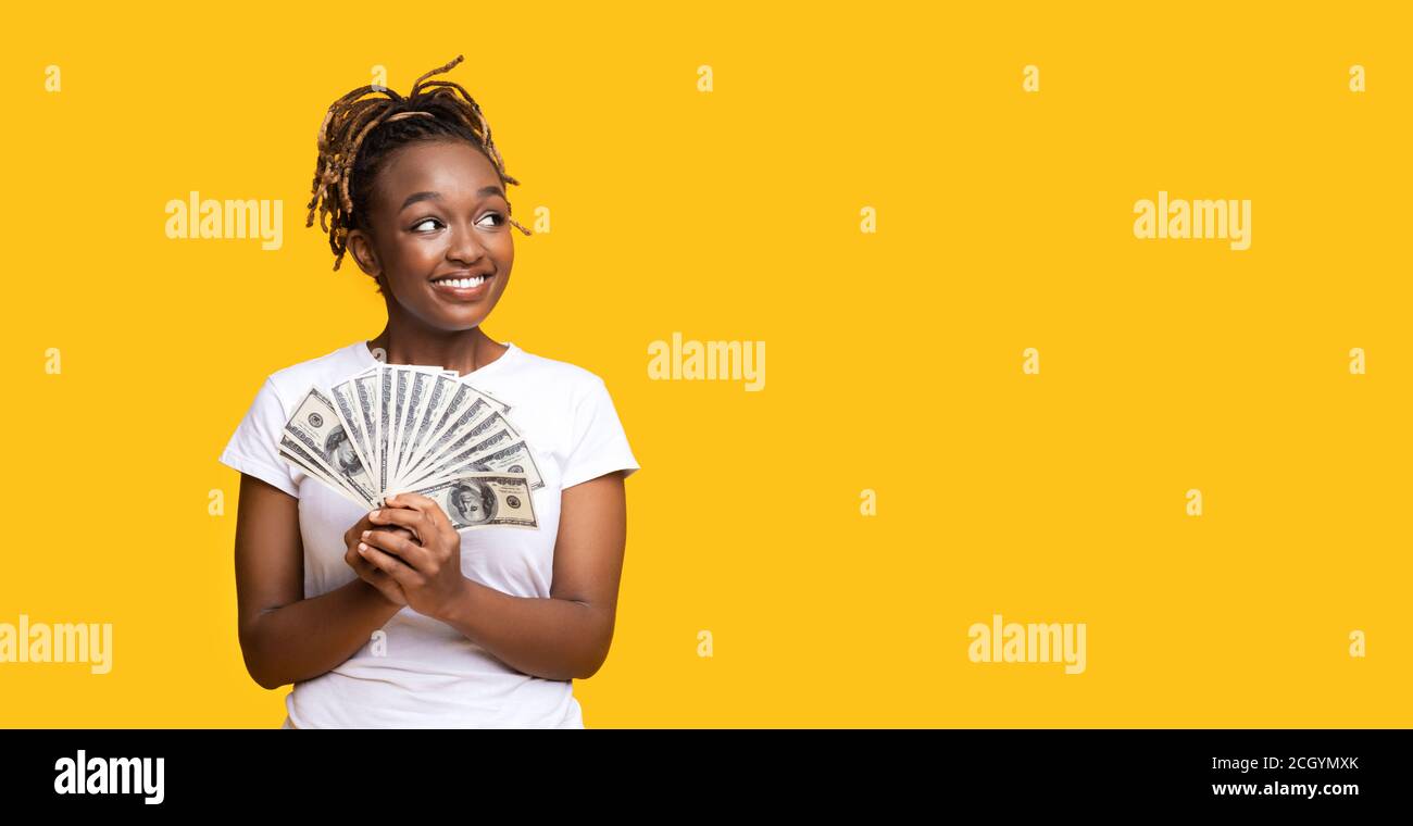 Emotionale schwarze Frau, die Geld hält und den Kopierraum betrachtet Stockfoto