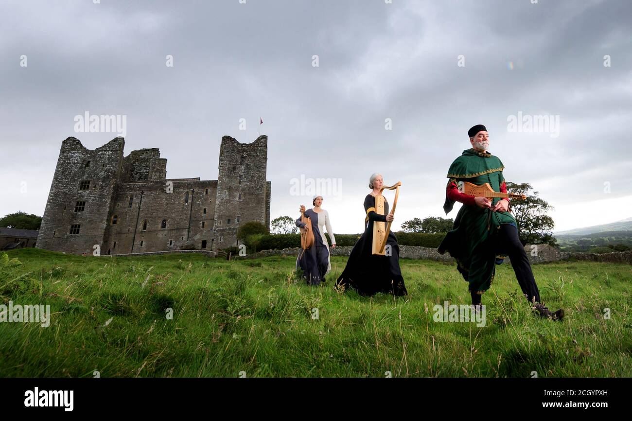 Von links nach rechts hält Theodora Hidalgo eine mittelalterliche Vielle, Cait Webb hält eine mittelalterliche Harfe und Chris Elmes mit einer Zitole, aus dem mittelalterlichen Ensemble Gaita, tragen traditionelle Kleidung auf dem Gelände von Castle Bolton in North Yorkshire, vor der Aufführung während der Medieval Music in the Dales, Englands Festival der mittelalterlichen Musik. Stockfoto