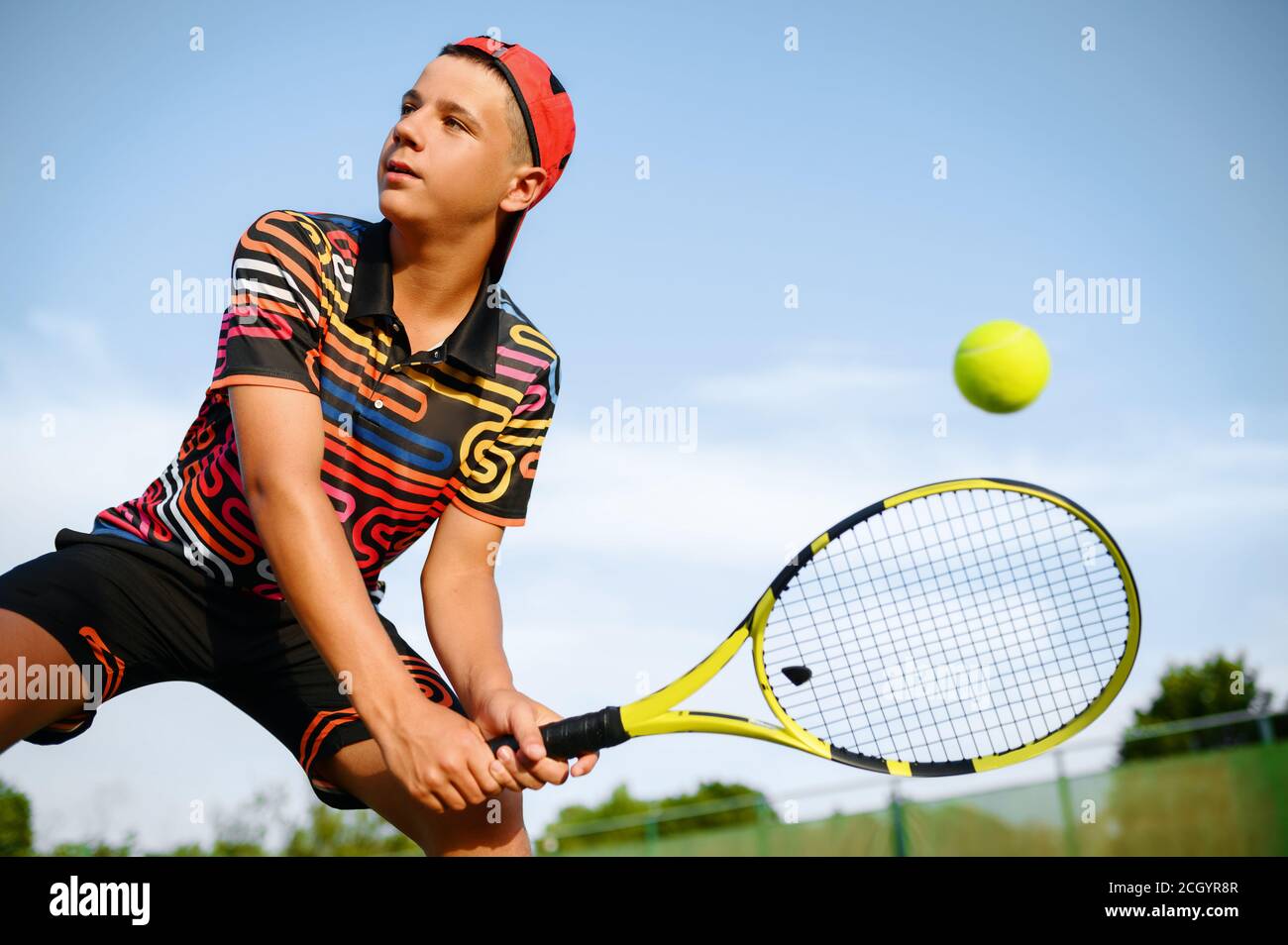 Junger männlicher Tennisspieler mit Schläger trifft den Ball Stockfoto