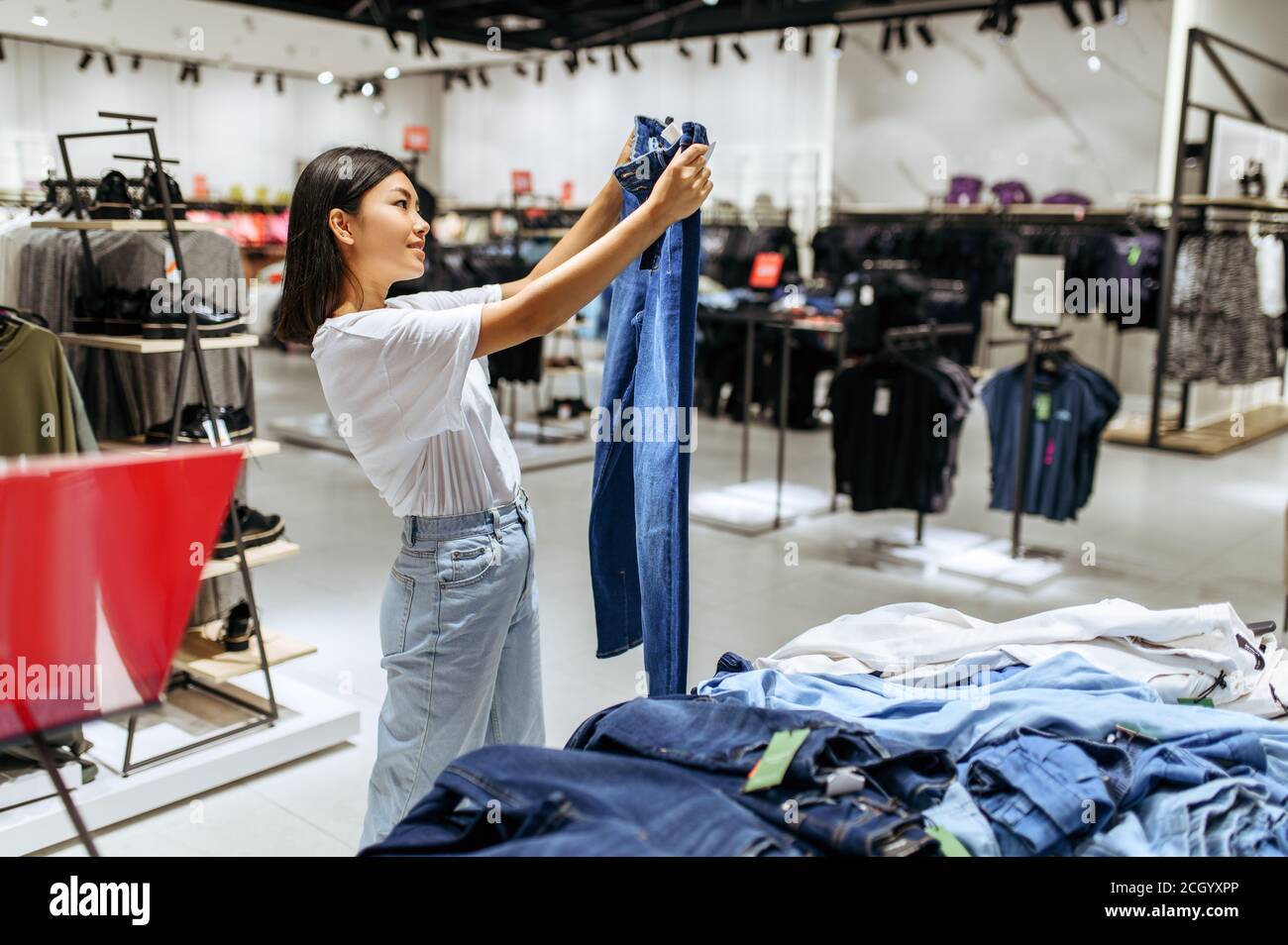 Fröhliche Frau Wahl Jeans im Bekleidungsgeschäft Stockfoto