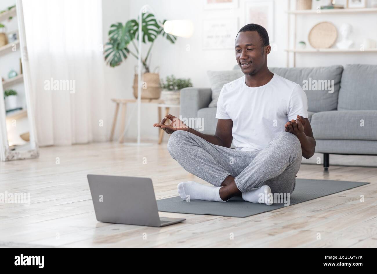 Lächelnder schwarzer Kerl mit Morgenmeditation zu Hause Stockfoto