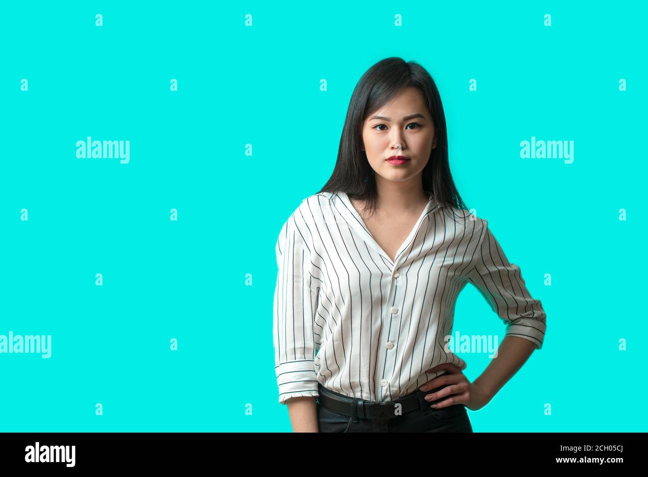 Asiatische junge Frau in hellweißer Bluse isoliert auf blauem Hintergrund. Casual hübsche Frau Blick auf die Kamera mit selbstbewussten Ausdruck. Stockfoto