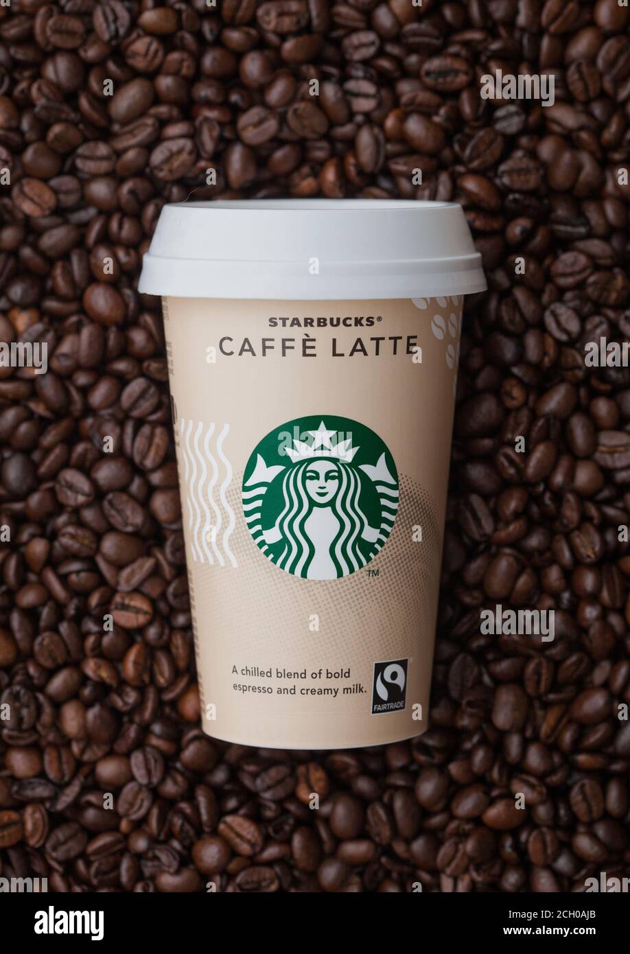 LONDON, UK - September 09, 2020: Papiertasse Starbucks Caffe Latte kalten Kaffee auf der Oberseite der frischen rohen Kaffeebohnen. Stockfoto
