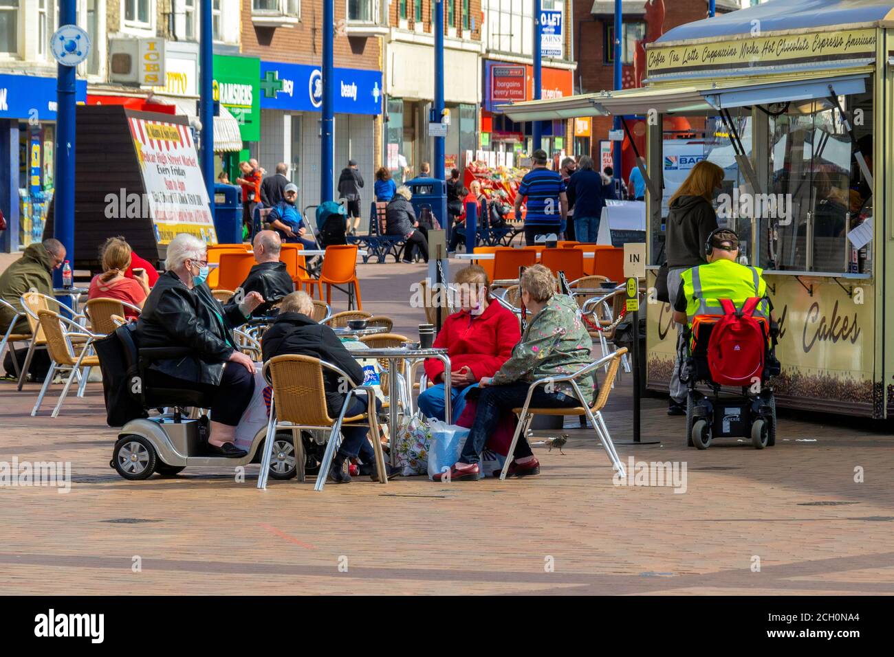 Shopper genießen die Sonne sitzen an Café-Tischen Redcar Cleveland North Yorkshire England Großbritannien Stockfoto