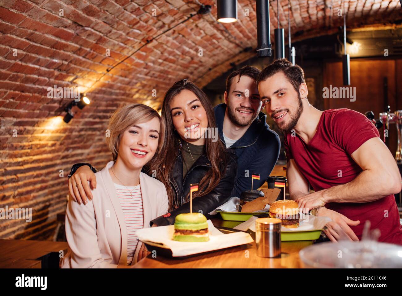 Portrait von fröhlichen jungen Freunden, die Nächte in einem modernen Pub auf rotem Backstein genießen. Stockfoto