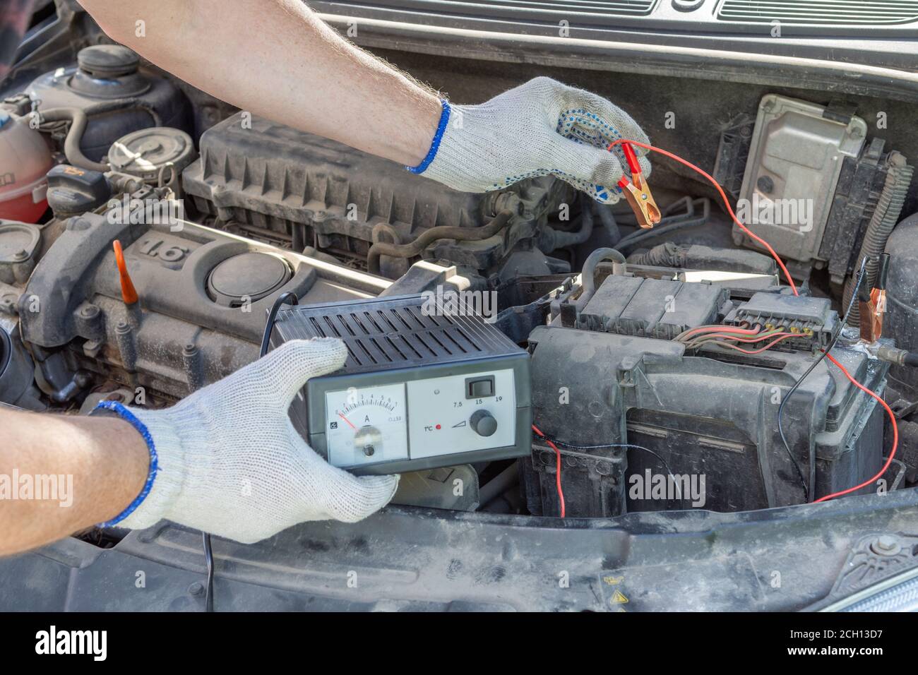Eine Nahaufnahme eines Mechanikers Hände mit Jumper-Kabel an einer Autobatterie. Fahrzeugcheck-Konzept Stockfoto