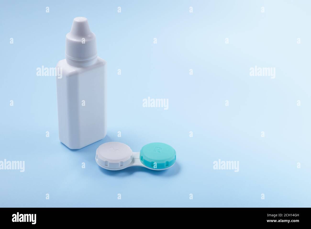 Kontaktlinsen und Linsenflüssigkeit auf blauem Hintergrund. Flasche mit Linsenlösung und Behälter für Kontaktlinsen. Copyspace Stockfoto