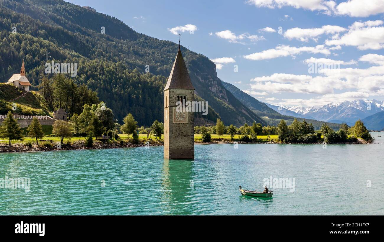 Fischer in seinem Boot in der Nähe des untergetauchten Glockenturms in Reschensee, Curon, Südtirol, Italien Stockfoto