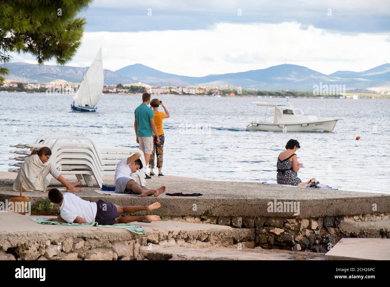 Vodice, Kroatien - 1. September 2020: Menschen, die sich in der Nebensaison am Strand entspannen und Boote im Meer Stockfoto