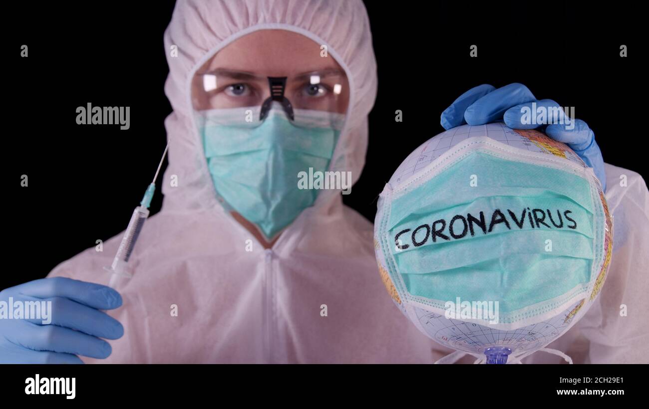 Coronavirus-Impfstoff. Mann in weißer Sicherheitsuniform, Maske und Brille mit Coronavirus-Impfstoffampulle und Spritze. COVID-19 Pandemieheilungskonzept Stockfoto